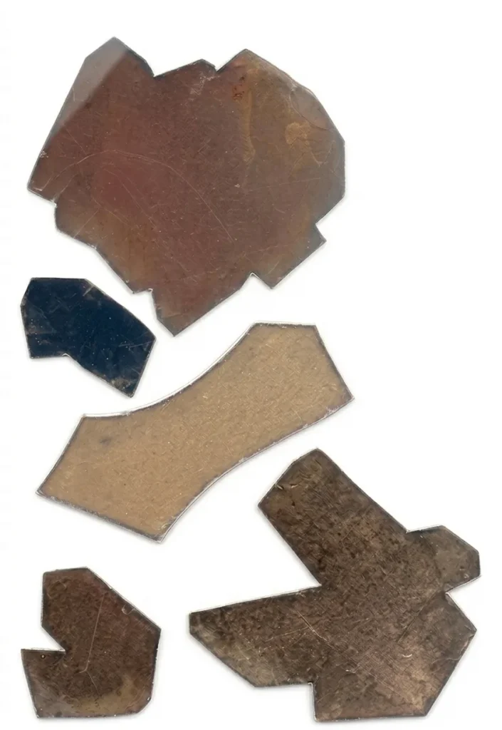 A collection of five irregular, flat mica block specimens in various shades of brown and dark grey.